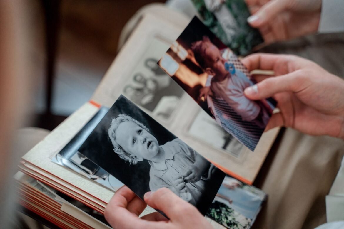 A pair of hands turning through old family photographs in an album.