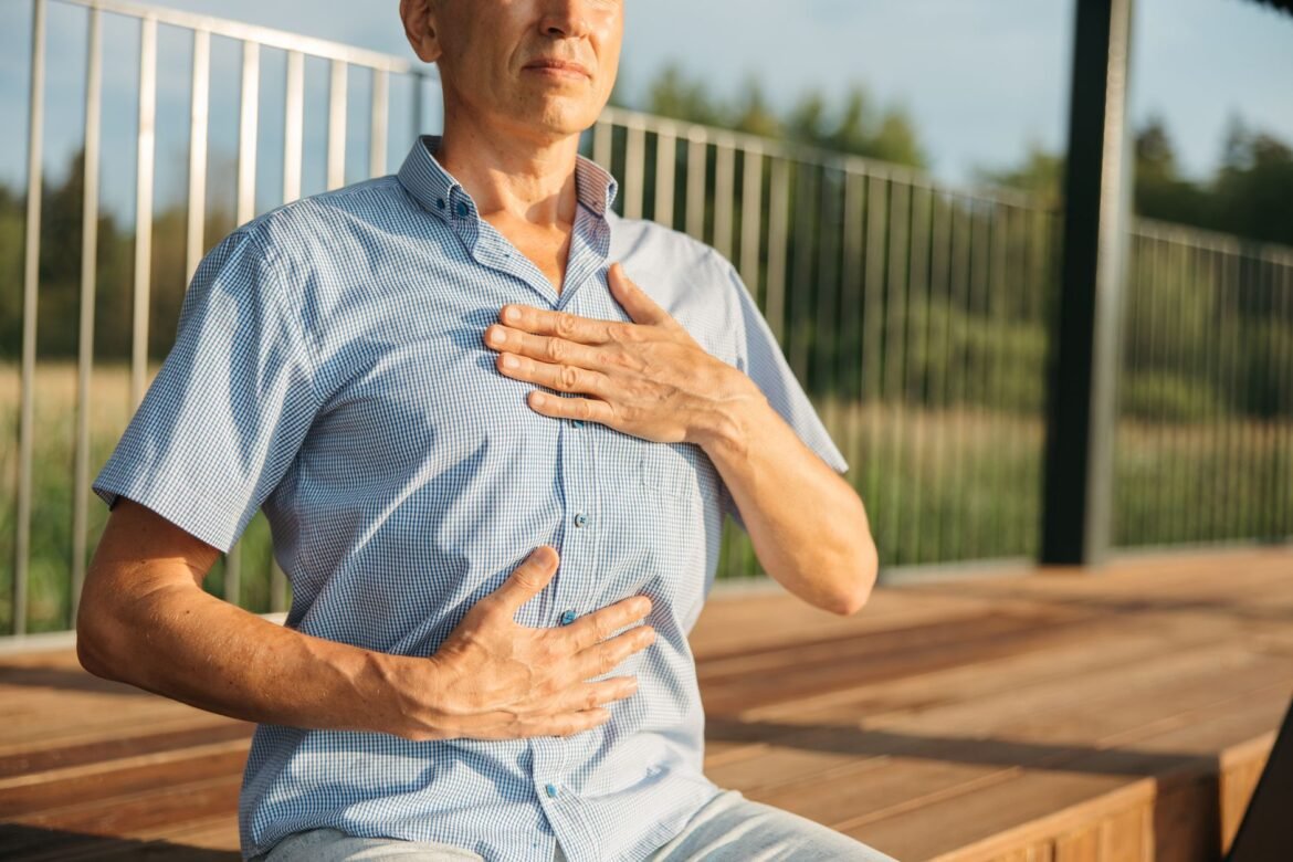A person resting one hand on their chest and the other on their abdomen while breathing slowly.