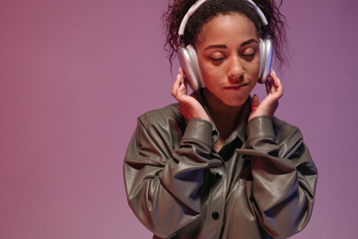A woman listening through over-ear headphones with her eyes closed.