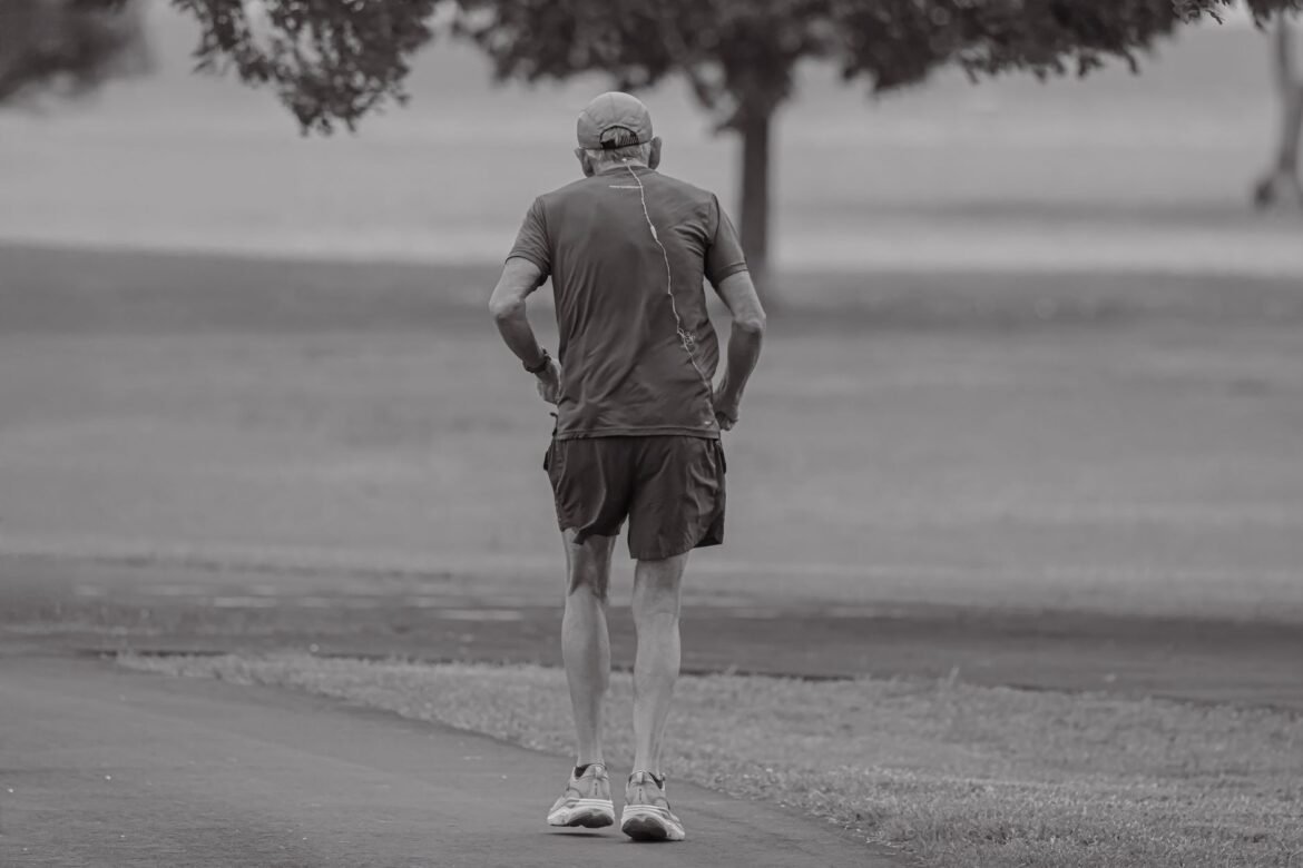 A man jogging alone through a quiet park at dawn.