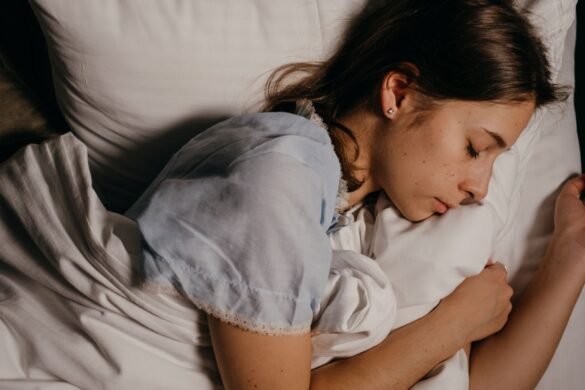 A person asleep on a white pillow in a dim room at night.