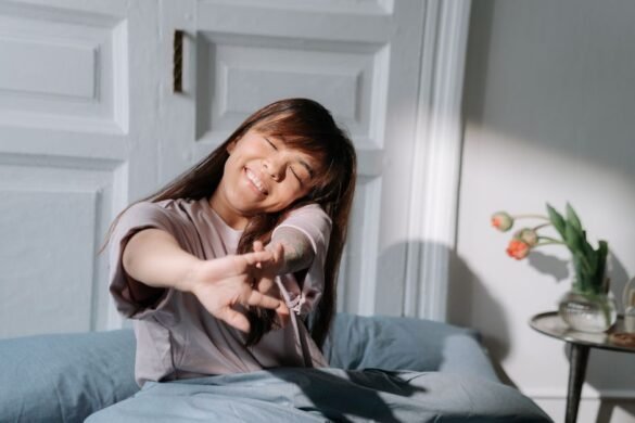 A woman stretching in soft morning light beside a bed