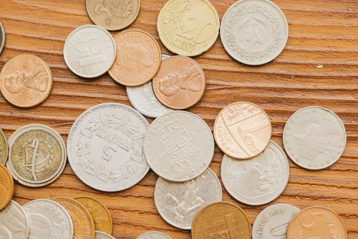 A scatter of worn everyday coins resting on a bare wooden surface