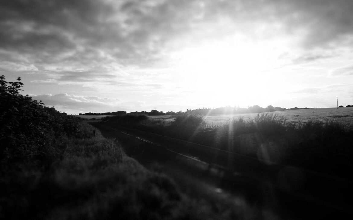 A broad open field stretching under a wide, bright sky
